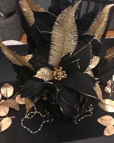 a black and gold flower with leaves on it's centerpiece, sitting on a table