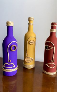 three different colored bottles sitting on top of a wooden table with rope wrapped around them