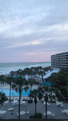 an aerial view of the beach and pool at dusk with palm trees in foreground