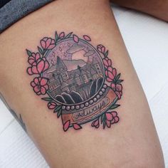 a woman's thigh with a castle in the middle and flowers around her leg