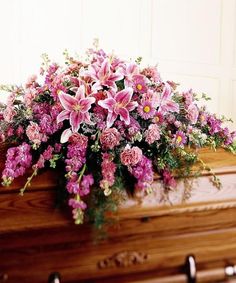 the casket is filled with pink flowers and greenery