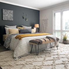 a bedroom with gray walls and white rugs on the floor next to a large bed