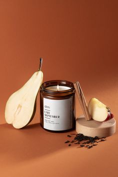 an apple next to a candle and some seeds on a brown background with a wooden spoon