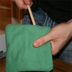 a person holding a toothbrush in their hand over a green bag on a table