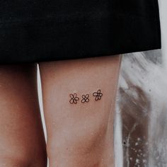 a woman's legs with three small flowers tattooed on her left side ribcage