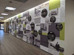 a large wall covered in lots of black and white pictures next to a hallway with wooden floors