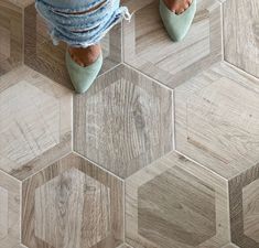 a person standing on top of a wooden floor next to a tiled floor with hexagonal tiles