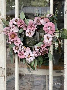 a heart - shaped wreath with pink flowers hangs on an old window sill in front of a stone wall