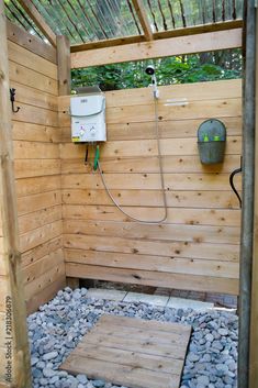 an outdoor shower with rocks and gravel in the ground, next to a wooden fence