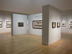 an empty room with several framed pictures on the wall and wooden floors in front of it