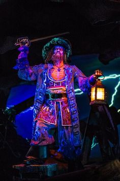 a man dressed as a pirate holding a lantern in his hand while standing on a stage