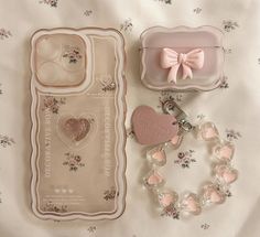 a pink heart shaped keychain, bracelet and case on a white floral sheet