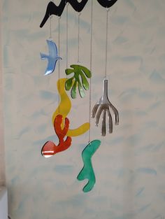 a colorful mobile hanging from the ceiling in front of a wall with birds and palm trees on it