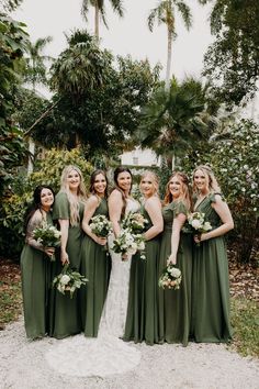 a group of women standing next to each other wearing green dresses and holding bouquets