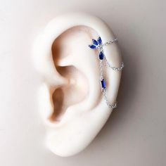 an ear with a chain attached to it and some blue beads hanging from the side