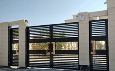 a black and white gate with gold bars on the top, in front of a building