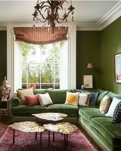 a living room filled with furniture and a chandelier hanging from the ceiling in front of a window