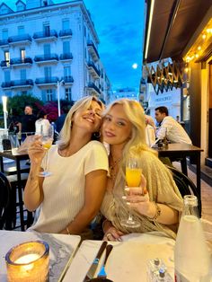 two women sitting at an outdoor table with drinks