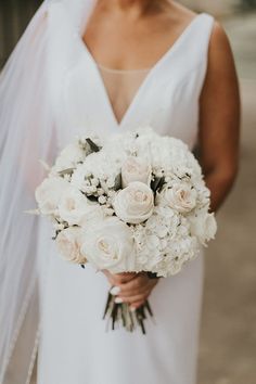 a bride holding a bouquet of white flowers