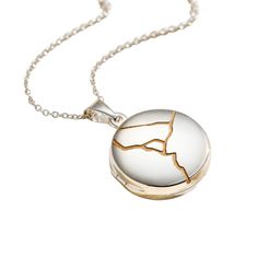 The lovely Sterling Silver Kintsugi Small Round Locket Necklace is inspired by the Japanese art of putting broken pottery pieces back together with gold.  The locket features a flat sterling silver circle front with a engraved Kintsugi inspired crack down the middle that is filled with gold fill. Kintsugi is a Japanese art form in which breaks and repairs are treated as part of the object's wonderful history. The repairs are highlighted as a special feature. Kintsugi isn't about perfection, it is about healing and seeing the beauty in imperfection. Inside the locket there is space for two photos. This necklace is made from Sterling silver. Locket is approx. 1. 8cm diameter. Chain is 18" Long. This necklace is made from Sterling silver. Each item is individually handmade to order in our Bri Silver Kintsugi, Round Locket Necklace, Beauty In Imperfection, Posh Totty, Dad Jewelry, Round Locket, Sterling Silver Locket, Silver Locket, June Birthstone Jewelry