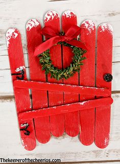 a red wooden sled with a wreath on top and a bow hanging from it