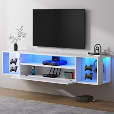 an entertainment center with a flat screen tv mounted on it's side and blue lighting