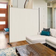 a living room with white couches and blue pillows on the floor next to a wooden coffee table