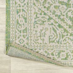 a green and white rug on top of a wooden floor