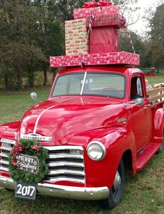 an old red truck with presents on the back