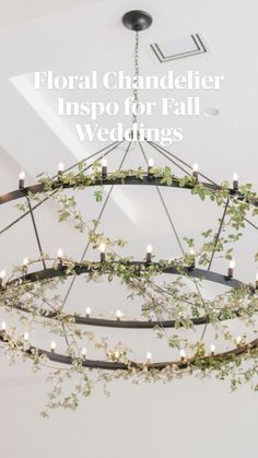 a chandelier hanging from the ceiling with greenery on it and candles lit