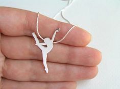 a hand holding a tiny white ballerina necklace