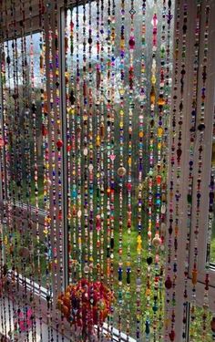 a window covered in lots of beads next to a grass field