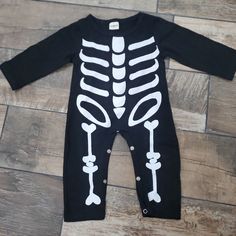 a baby's black skeleton bodysuit is laying on the floor