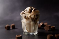 an ice cream sundae in a glass with chocolate chunks on the table next to it