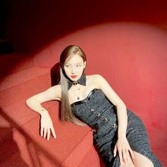 a woman in a black dress is sitting on some stairs and posing for the camera