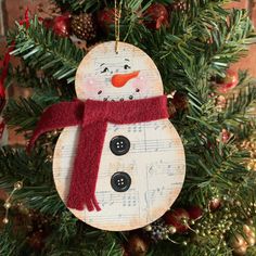 a snowman ornament hanging from a christmas tree with music notes on it