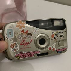 a person holding up a camera with stickers on it