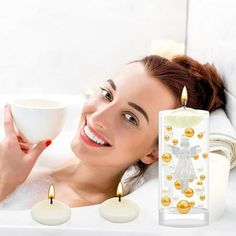 a woman laying in a bathtub next to candles and a cup