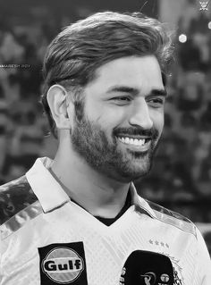 a black and white photo of a man with a goatee smiling at the camera