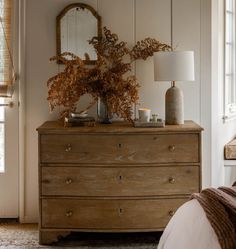 a wooden dresser sitting next to a bed with a mirror on it's side