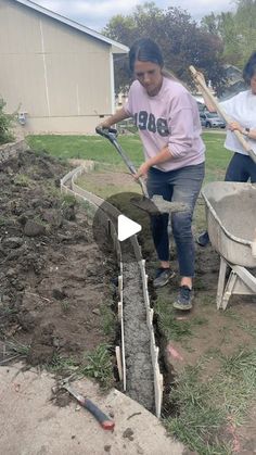 two women are digging in the dirt with shovels