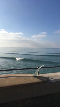 there is a surfboard leaning against the rail near the water's edge,