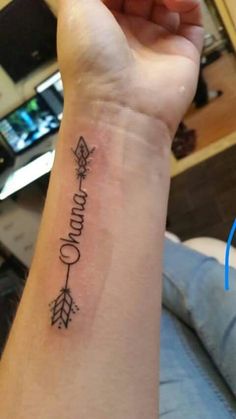 a woman's wrist tattoo with an arrow and the word grandma written in cursive writing