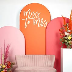 a pink couch sitting in front of a wall with the words miss to mrs written on it