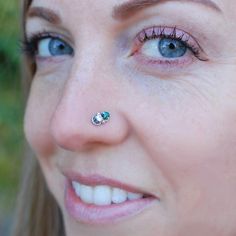 a close up of a woman with a nose ring and piercing on her nose looking at the camera