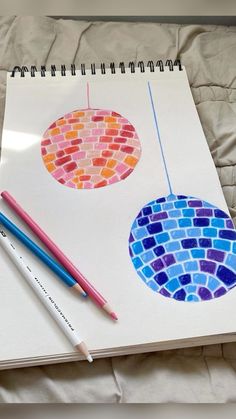 an open notebook with two different colored circles on it next to pencils and markers