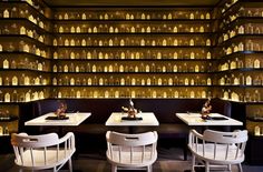 an empty restaurant with tables and chairs in front of shelves full of bottles on the wall