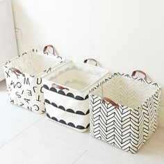 three storage baskets sitting on the floor in front of a white wall with black and white designs