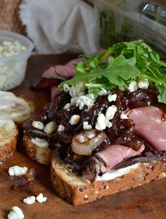 a sandwich with meat, cheese and lettuce sitting on a wooden cutting board