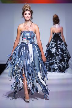 a woman walking down a runway wearing a dress made out of duct tape and paper